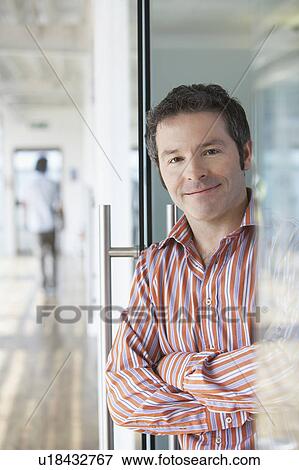 Stock Photo - Office worker standing in doorway, portrait. Fotosearch
