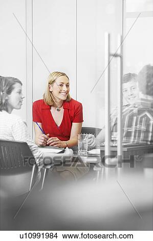 Picture - Office workers sitting around conference table (isolated colour). Fotosearch