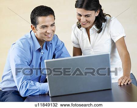 Stock Image - Office Workers Using Laptop Together. Fotosearch