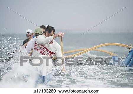 Stock Image - Outrigger canoeing team on water. Fotosearch