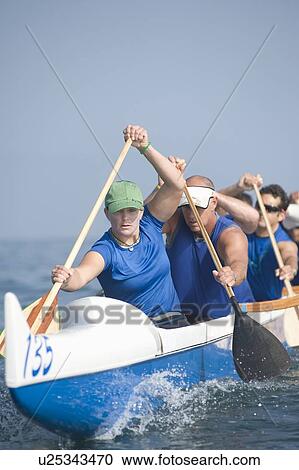 Stock Image - Outrigger canoeing team on water. Fotosearch