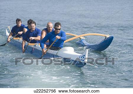 Stock Photograph - Outrigger canoeing team on water. Fotosearch