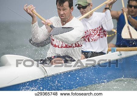 Stock Photo - Outrigger canoeing team raise oars. Fotosearch