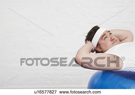 Stock Photo - Overweight Man doing sit-ups on Exercise Ball. Fotosearch