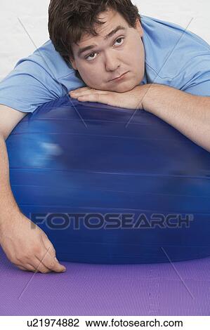 Stock Image - Overweight Man Resting on Exercise Ball, portrait. Fotosearch