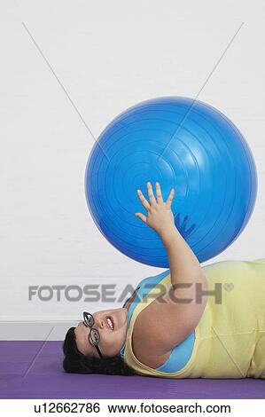 Overweight Woman lying down Holding up Exercise Ball View Large Photo Image Stock Photograph - Overweight Woman lying down Holding up Exercise Ball. Fotosearch