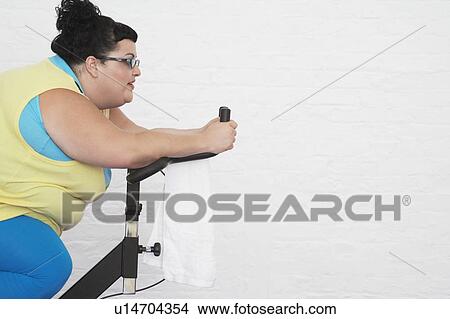 Picture - Overweight Woman on Exercise Bike. Fotosearch