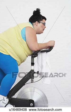 Stock Photo - Overweight Woman on Exercise Bike. Fotosearch