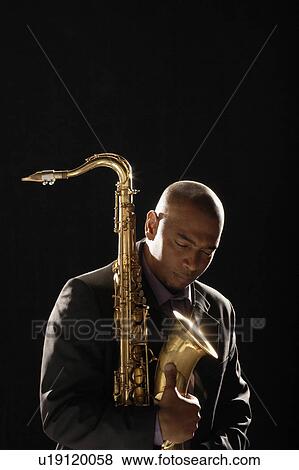 Stock Photo - Pensive man holding saxophone, eyes closed. Fotosearch