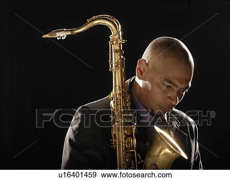 Pensive man holding saxophone, looking down, close-up View Large Photo Image Stock Photo - Pensive man holding saxophone, looking down, close-up. Fotosearch