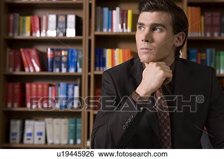 Stock Photograph - Pensive man wearing suit in library. Fotosearch