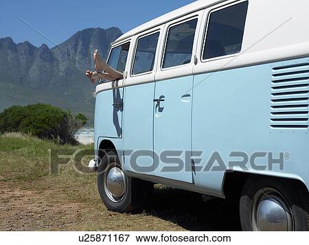 Stock Photo - Person in parked camper van, feet sticking out of window. Fotosearch