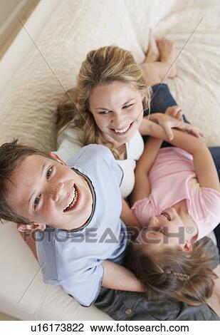 Raised view of laughing brother and sister piled on mother's lap with son smiling up to camera View Large Photo Image Stock Image - Raised view of laughing brother and sister piled on mother's lap with son smiling up to camera. Fotosearch