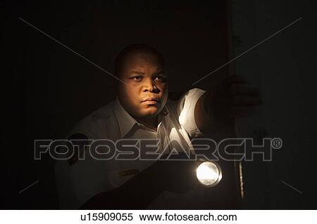 Stock Photography - Security guard investigates with flashlight. Fotosearch