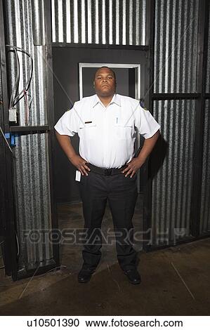 Security guard stands at corrugated metal doorway View Large Photo Image Stock Image - Security guard stands at corrugated metal doorway. Fotosearch
