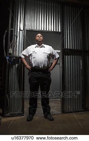 Security guard stands at corrugated metal doorway View Large Photo Image Stock Image - Security guard stands at corrugated metal doorway. Fotosearch