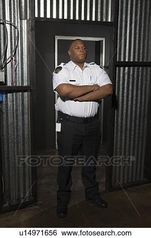 Security guard stands at corrugated metal doorway View Large Photo Image Stock Photograph - Security guard stands at corrugated metal doorway. Fotosearch