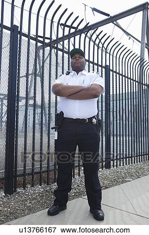 Security guard stands at strengthened prison fence View Large Photo Image Stock Photo - Security guard stands at strengthened prison fence. Fotosearch