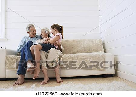 Senior man and woman sitting with granddaughter on woman's knee on couch View Large Photo Image Stock Image - Senior man and woman sitting with granddaughter on woman's knee on couch. Fotosearch