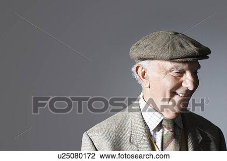 Stock Image - Senior man in flat cap, head and shoulders, in studio. Fotosearch