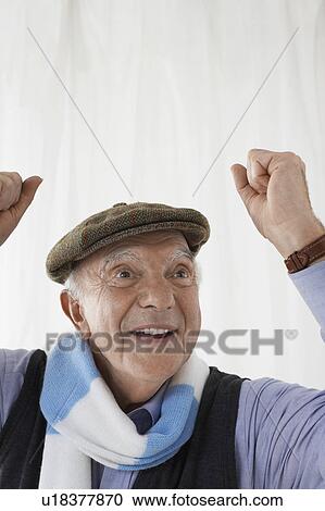 Stock Image - Senior man in football scarf, celebrating in studio, head and shoulders. Fotosearch