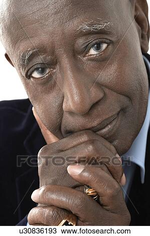 Stock Image - Senior Man in studio, close up, hands on chin. Fotosearch