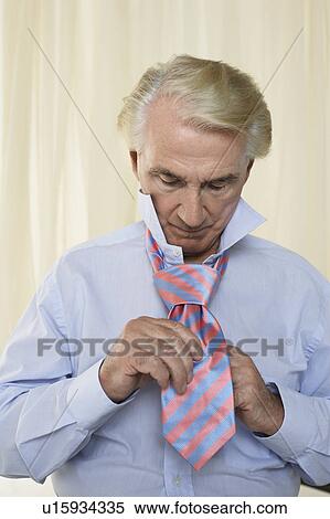 Stock Photography - Senior man tying tie, half length. Fotosearch