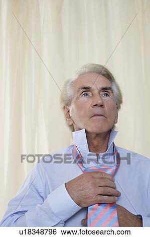 Stock Photograph - Senior man tying tie, head and shoulders. Fotosearch