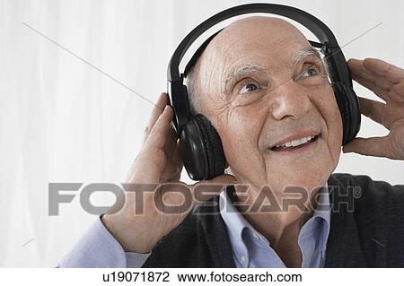 Stock Image - Senior man wearing head phones in studio. Fotosearch