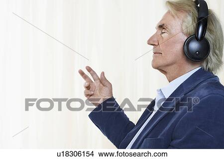 Senior man wearing headphones, profile, in studio View Large Photo Image Picture - Senior man wearing headphones, profile, in studio. Fotosearch