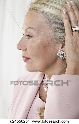 Picture - Senior woman holding back hair, in studio, profile. Fotosearch