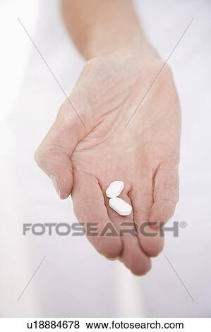 Stock Photo - Senior woman holding pills in hand, close-up on hand. Fotosearch