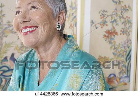 Stock Photograph - Senior woman in dressing gown in living room, head and shoulders. Fotosearch