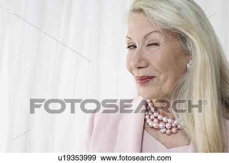 Stock Photo - Senior woman winking in studio, head and shoulders. Fotosearch