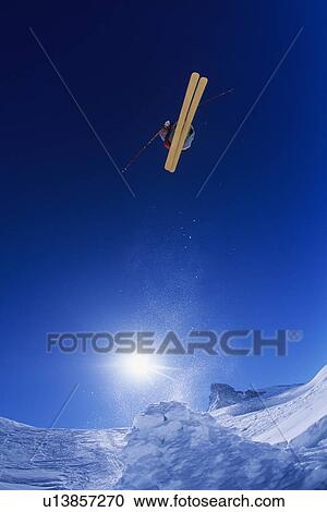 Stock Image - Skier jumping, against blue sky. Fotosearch