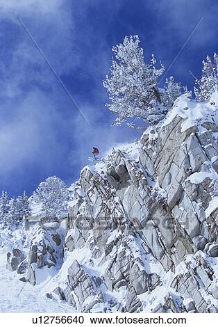 Stock Image - Skier jumping from cliff in mountains. Fotosearch