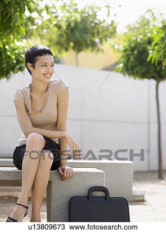 Smiling Businesswoman sitting on bench in plaza View Large Photo Image Stock Image - Smiling Businesswoman sitting on bench in plaza. Fotosearch