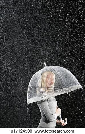 Stock Photo - Smiling businesswoman Standing Under Umbrella during rain. Fotosearch
