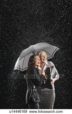 Smiling Businesswomen Standing Under Umbrella together during rain View Large Photo Image Stock Photo - Smiling Businesswomen Standing Under Umbrella together during rain. Fotosearch