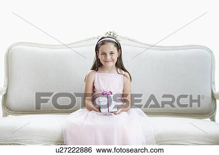 Smiling girl in tutu sitting on sofa holding gift, portrait View Large Photo Image Stock Photograph - Smiling girl in tutu sitting on sofa holding gift, portrait. Fotosearch