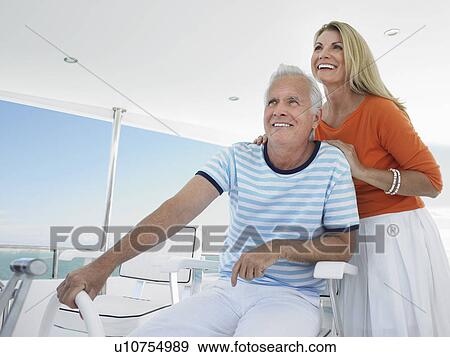 Smiling middle-aged couple at helm of yacht View Large Photo Image Stock Photo - Smiling middle-aged couple at helm of yacht. Fotosearch