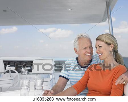Stock Image - Smiling middle-aged couple on yacht. Fotosearch