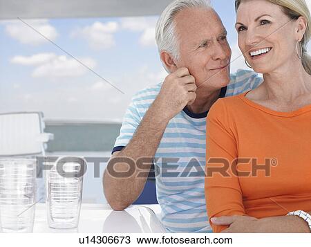 Stock Image - Smiling middle-aged couple outdoors, portrait. Fotosearch