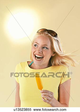 Stock Photography - Smiling woman holding popsicle on hot Summer Day. Fotosearch