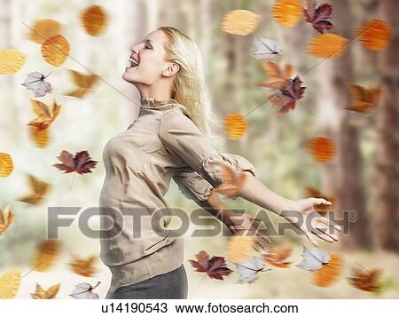 Stock Image - Smiling woman standing, arms outspread, profile. Fotosearch