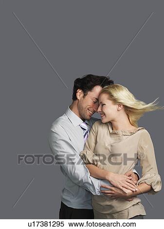 Stock Photography - Smiling Young Couple embracing, hair blowing in breeze. Fotosearch