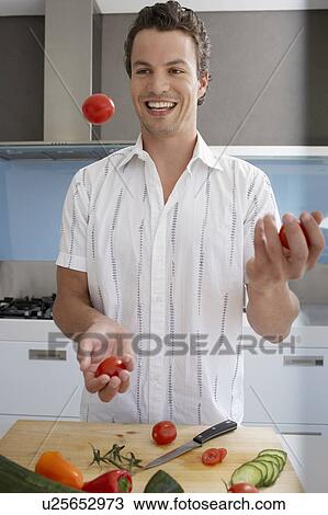 Smiling, young man juggling cherry tomatoes in kitchen View Large Photo Image Stock Image - Smiling, young man juggling cherry tomatoes in kitchen. Fotosearch