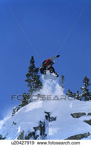 Stock Photo - Snowboarder jumping from mountain ledge. Fotosearch