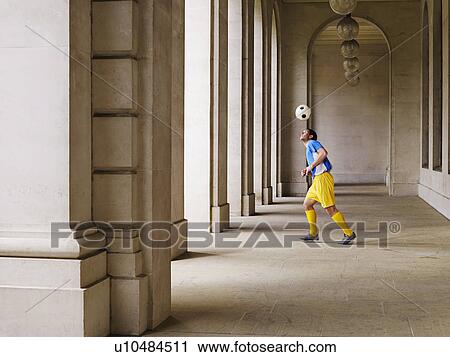 Stock Image - Soccer player bouncing ball off head in portico. Fotosearch
