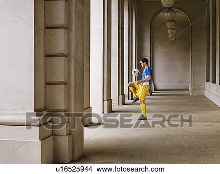 Soccer player bouncing ball off knee in portico View Large Photo Image Picture - Soccer player bouncing ball off knee in portico. Fotosearch